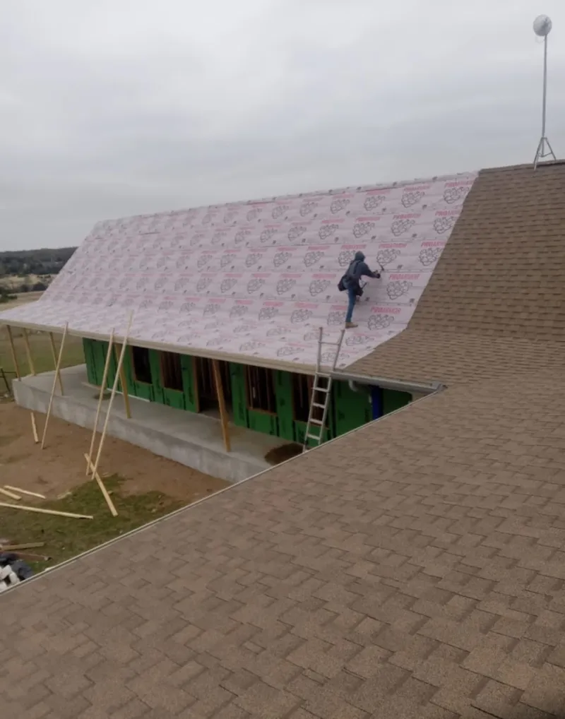 Worker preparing underlayment for a metal roof installation in South Hadley